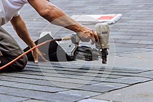 Air pneumatic nail gun used by roofer to install new asphalt bitumen a shingles