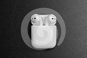 Air Pods with Wireless Charging Case. New Airpods 2019 on black background. entangled 3.5 headphones - Image photo