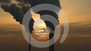 Air pollution. clouds of smoke coming from the chimneys of the plant with beautiful golden yellow lighting of setting sun. Drone