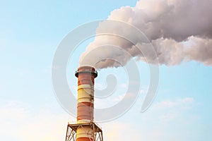 Air pollution by smoke coming out of a large factory chimney. A close-up of smoke coming out of chimneys against the blue sky. Air