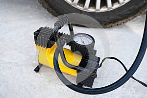 Air pump inflating a wheel of a broken car, car breakdown concept