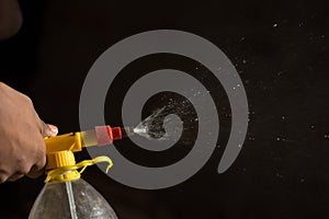 Air pump water spray bottle. close up of a spraying water drops isolated on black background