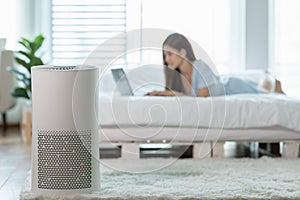 Air purifier in bed room for clean dust and fresh air with woman working with computer laptop and relax in background