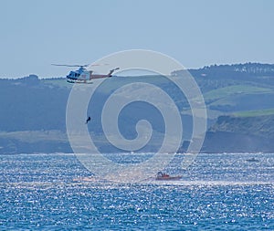 Air sea rescue helicopter, over the coast of Santander, accompanied by a rescue boat