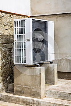 Air source heat pump installed outside of old renovated house, green renewable energy concept of heat pump