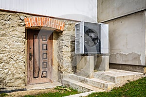 Air source heat pump installed outside of old renovated house, green renewable energy concept of heat pump