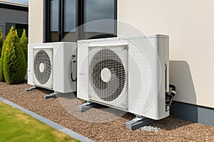 Air source heat pumps installed on the garden front of a modern house. Renewable energy concept