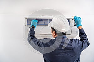 Air technician service checking and repairing air conditioner on white wall. Service concept of an air conditioner technician