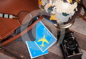 Air ticket, globe and bag on wood background