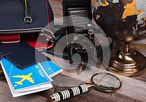 Air ticket, globe and bag on wood background