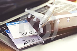 Air tickets and passports near laptop computer and airplane on table. Online ticket booking concept
