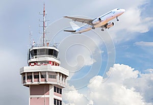 Air traffic control tower in international airport with passenger airplane jet taking off