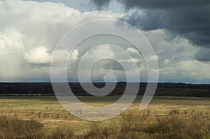 Air view from the hill to spring pasture valley under a moody cloudy sky. Landscape of remote places yellow blue motive