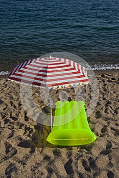 Airbed and sun umbrella on a beach photo