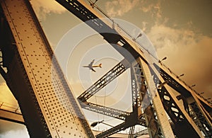 Airbourne passenger jet viewed through bridge superstructure