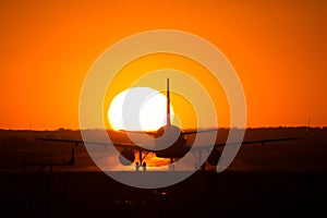 Airbus A320 airplane silhouette at sunset , on runway