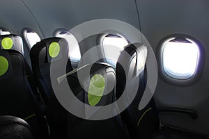 aircraft cabin, seats, portholes, empty plane without passengers. Rows of gray leather seats and windows in the aisle of