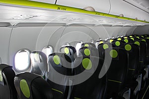 aircraft cabin, seats, portholes, empty plane without passengers. Rows of gray leather seats and windows in the aisle of