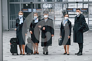 Aircraft crew in work uniform is together outdoors in the airport