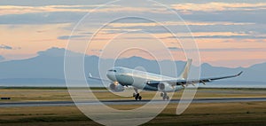 Aircraft landing at YVR at dusk with mountains in the background.