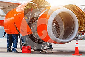 Aircraft Maintenance Mechanics Inspecting and Working on Airplane Jet Engine on Apron.