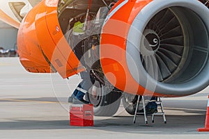 Aircraft Maintenance Mechanics Inspecting and Working on Airplane Jet Engine on Apron.