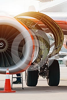 Aircraft Maintenance Mechanics Inspecting and Working on Airplane Jet Engine on Apron.