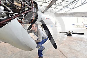 Aircraft mechanic repairs an aircraft engine in an airport hangar photo