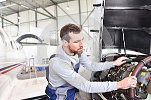 Aircraft mechanic repairs an aircraft engine in an airport hangar