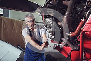 Aircraft mechanic repairs an aircraft engine in an airport hangar