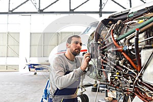 Aircraft mechanic repairs an aircraft engine in an airport hangar