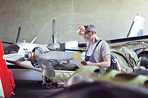 Aircraft mechanic repairs an aircraft engine in an airport hangar