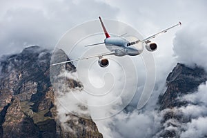 Aircraft, mountains in overcast sky. Airplane