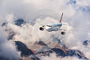 Aircraft, mountains in overcast sky. Airplane