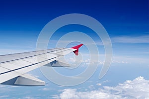 Aircraft's wing in blue sky above white clouds