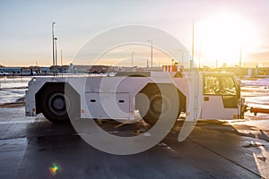 Aircraft tow tractor at the airport apron in the light of evening sun