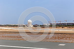 Aircraft tracking radar tower at Muscat airport. Runway and tarmac at Muscat airport at day