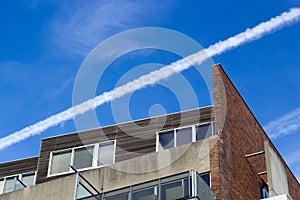Aircraft vapour trail over an apartment block