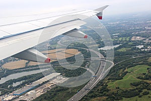 Aircraft wing in flight over motorway junction