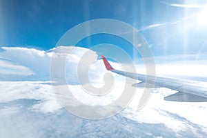 Aircraft wing flying above the beautiful clouds with sunlight in