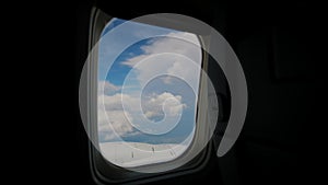 Aircraft Wing of flying in clouds and blue sky airplan. passenger porthole windows.