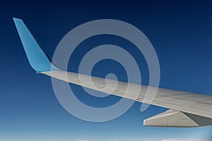 Aircraft wing view from airplane window seat. Blue sky and cloud