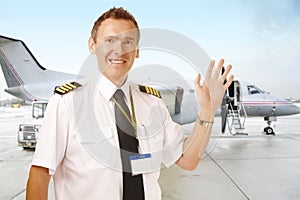 Airline pilot at the airport waving