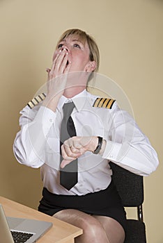 Airline pilot checking the time and yawning