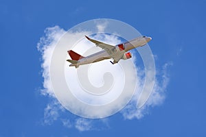 An airline plane in the blue sky flying in front of a big white cloud. Image with copy space