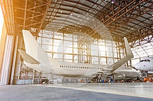 Airliner aircraft in a hangar with an open gate to the service.