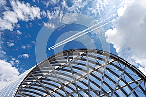 Airliner with Contrails Flying Above a Modern Airport