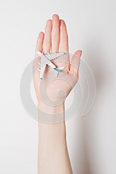 Airliner on the female palm on a light background. Concept of safe flights