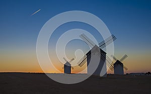 Airliner flying over windmills of Campo de Criptana, Spain