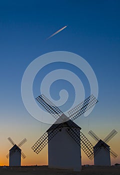 Airliner flying over windmills of Campo de Criptana, Spain